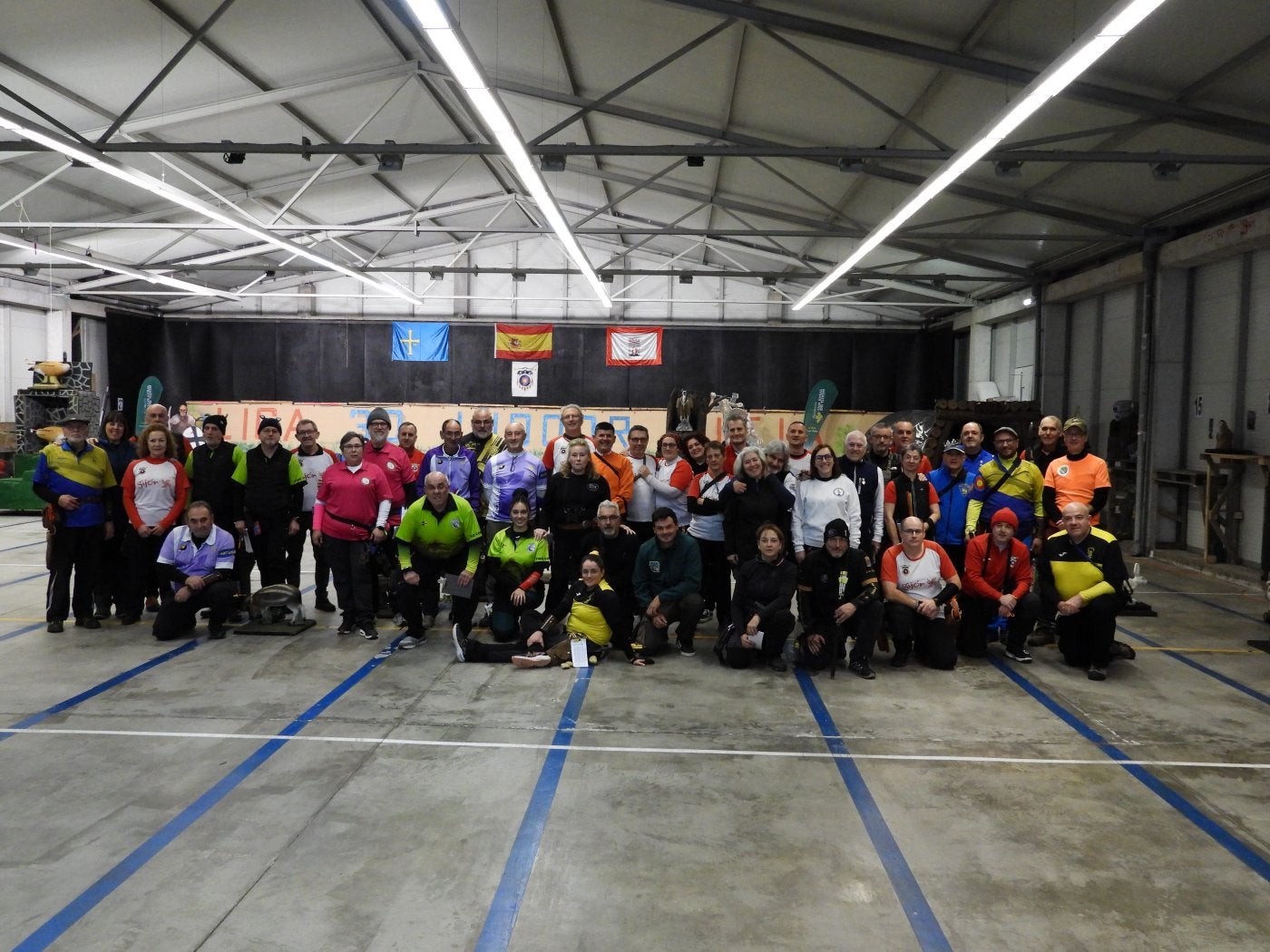 Arriba, foto de grupo con parte de los participantes. A la izquierda, un tirador durante la competición.