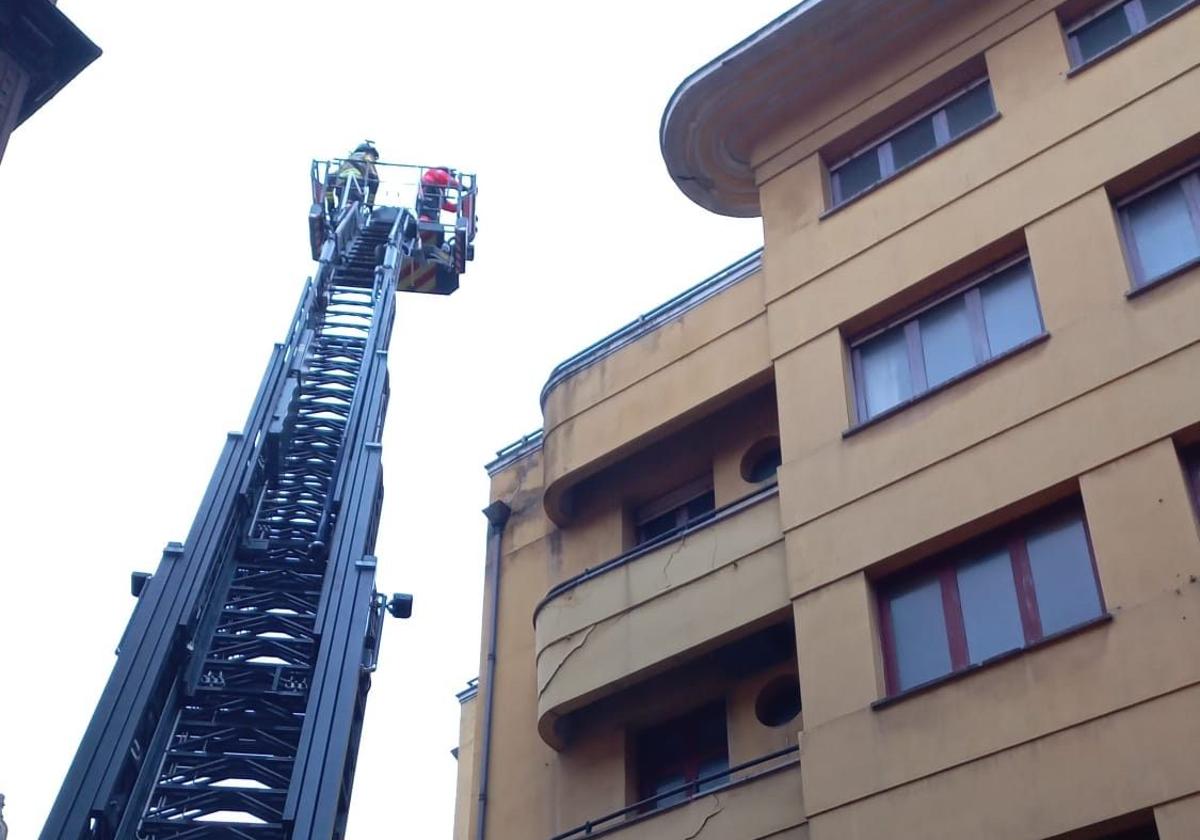 Efectivos de bomberos trabajan en la parte superior del edificio.