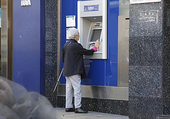 Una mujer saca dinero de un cajero.