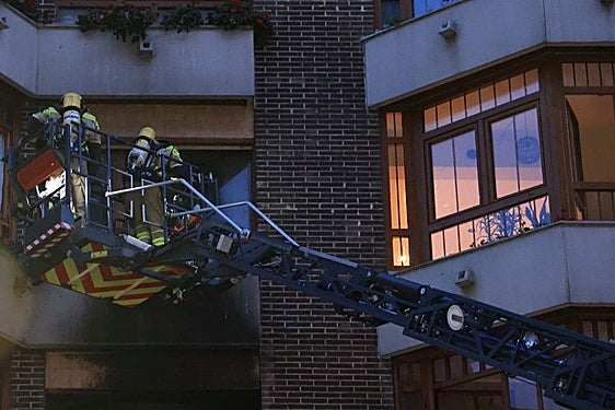 Los bomberos acceden al piso incendiado.