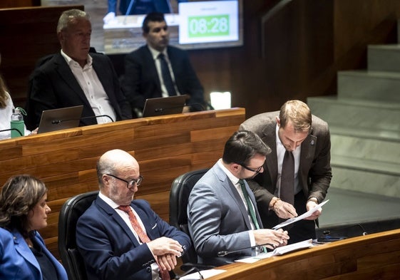 Adrián Pumares, de pie, muestra unas notas a Álvaro Queipo en la Junta General.