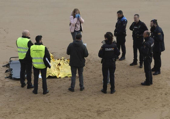 Agentes de la Policía Nacional y Local, junto al cuerpo hallado en la arena de la playa de San Lorenzo.