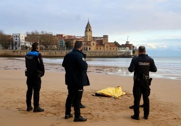 Agentes de la Policía Nacional y Local, junto al cuerpo hallado en la arena de la playa de San Lorenzo.