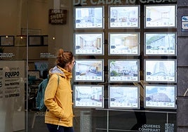 Una muejer observa los anuncios de una inmobiliaria.
