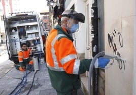 El operario de Emulsa elimina una de las pintadas en las fachadas de Gijón.