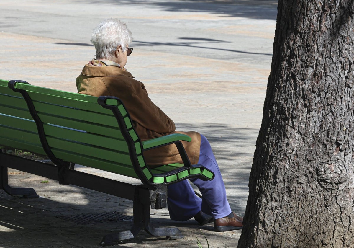 Una señora descansa en un banco al sol, en Oviedo.