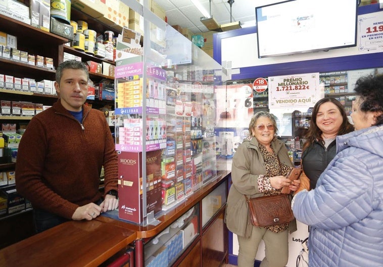 Iván Rodríguez, dueño del estanco de La Camocha que despachó el boleto premiado en la Bonoloto, este lunes, junto a tres clientas.