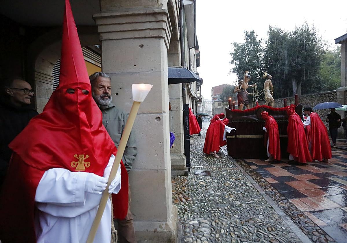 Los cofrades tratan de proteger el paso de Jesús azotado bajo los soportales tras el aguacero.