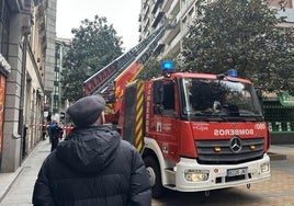 Un hombre observa la intervención de los bomberos en la calle Corrida de Gijón.