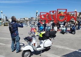 Participantes en los Vespa World Days de Gijón, fotografiándose ante las letronas.