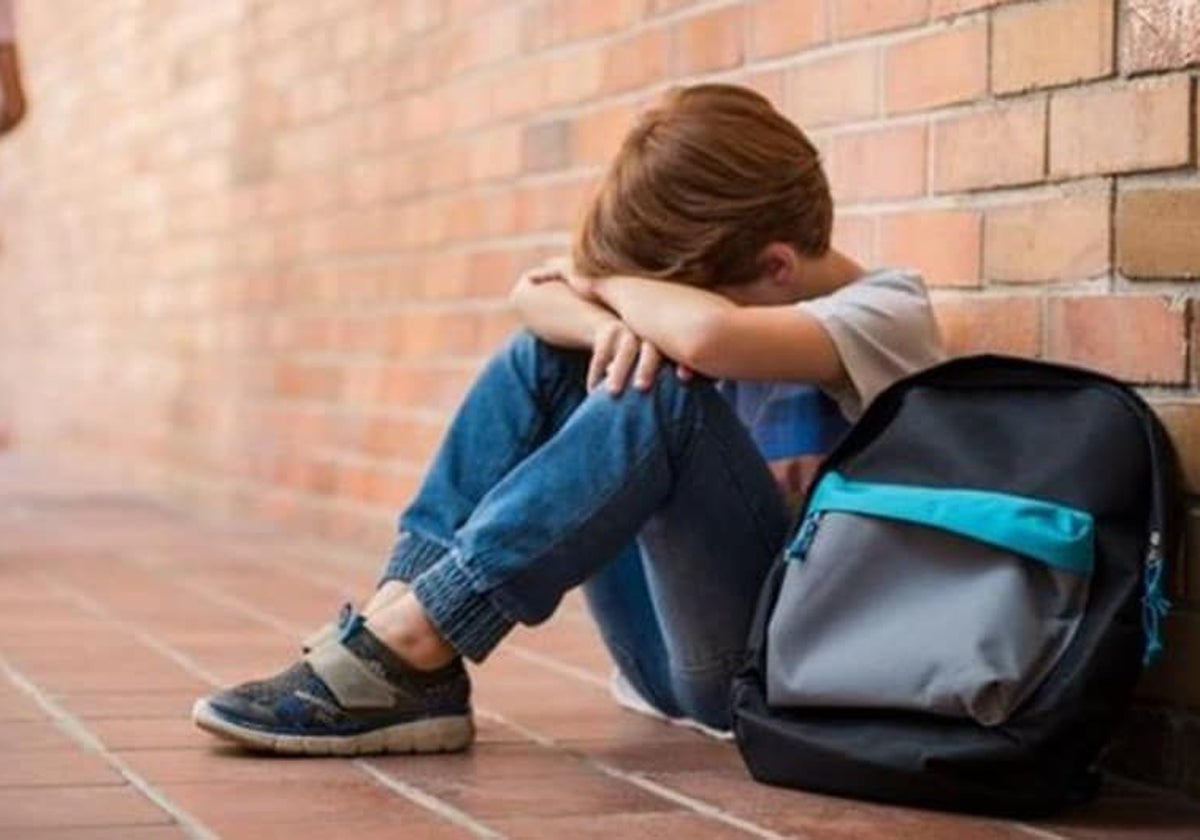 Un pequeño llora, solo, sentado en el suelo del colegio.