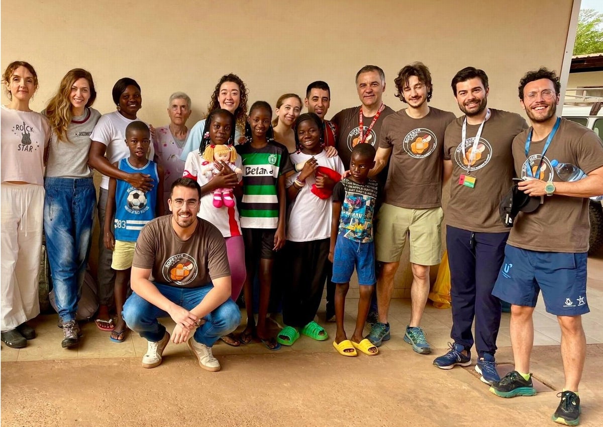 Imagen secundaria 1 - Arriba, los profesionales que participaron en la misión de voluntariado promovida por Sopesur en Guinea-Bisáu, entre ellos Antonio Hedrera (segundo por la derecha) y Álvaro Regueira (agachado). Sobre estas líneas, Pabelinho señala el escudo del Sporting que luce en su pecho. 