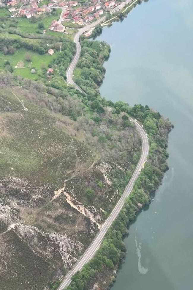 Dos manchas de aceite marcan la zona en la que el helicóptero se sumergió en las aguas del embalse de Tanes, cuya aportación a la red de agua potable de Asturias se ha cortado por seguridad. En la zona superior de la foto, la localidad casina de Tanes.