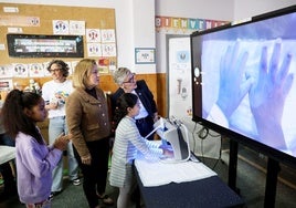 Las consejeras Lydia Espina y Soledad Saavedra observan las manos de una escolar bajo la cámara ultravioleta para comprobar si están limpias.