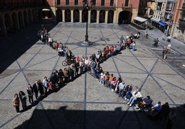 Decenas de personas forman una equis solidaria en la plaza Mayor de Gijón.