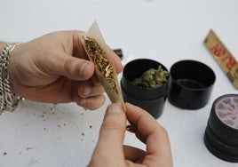 Un joven liándose un porro con marihuana.