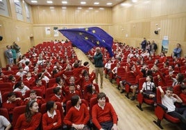 Un alumno del Codema ondea la bandera de la Unión Europea en el salón de actos del centro escolar.