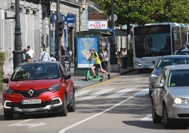 Un joven, por la acera en uno de los patinetes del servicio de alquiler.
