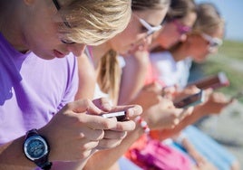 Varios adolescentes atentos a sus teléfonos móviles.