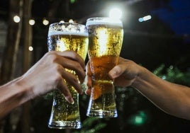 Dos personas brindan con unas cañas.