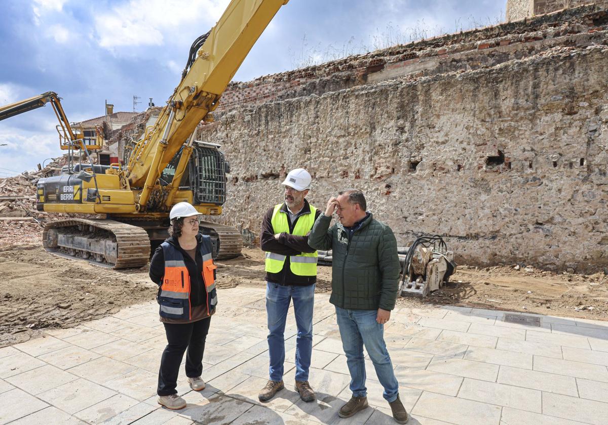 Noelia Fernández y Alejandro García conversan con el concejal Pelayo García ante un tramo de muralla descubierto.