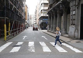 Una mujer cruza un paso de peatones en la calle Munuza, que reducirá su calzada a un carril.