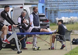 El fisio Abel Canteli trata a Jose Martínez sobre la camilla, con Kevin Bautista a la derecha ejercitándose en una bicicleta estática.