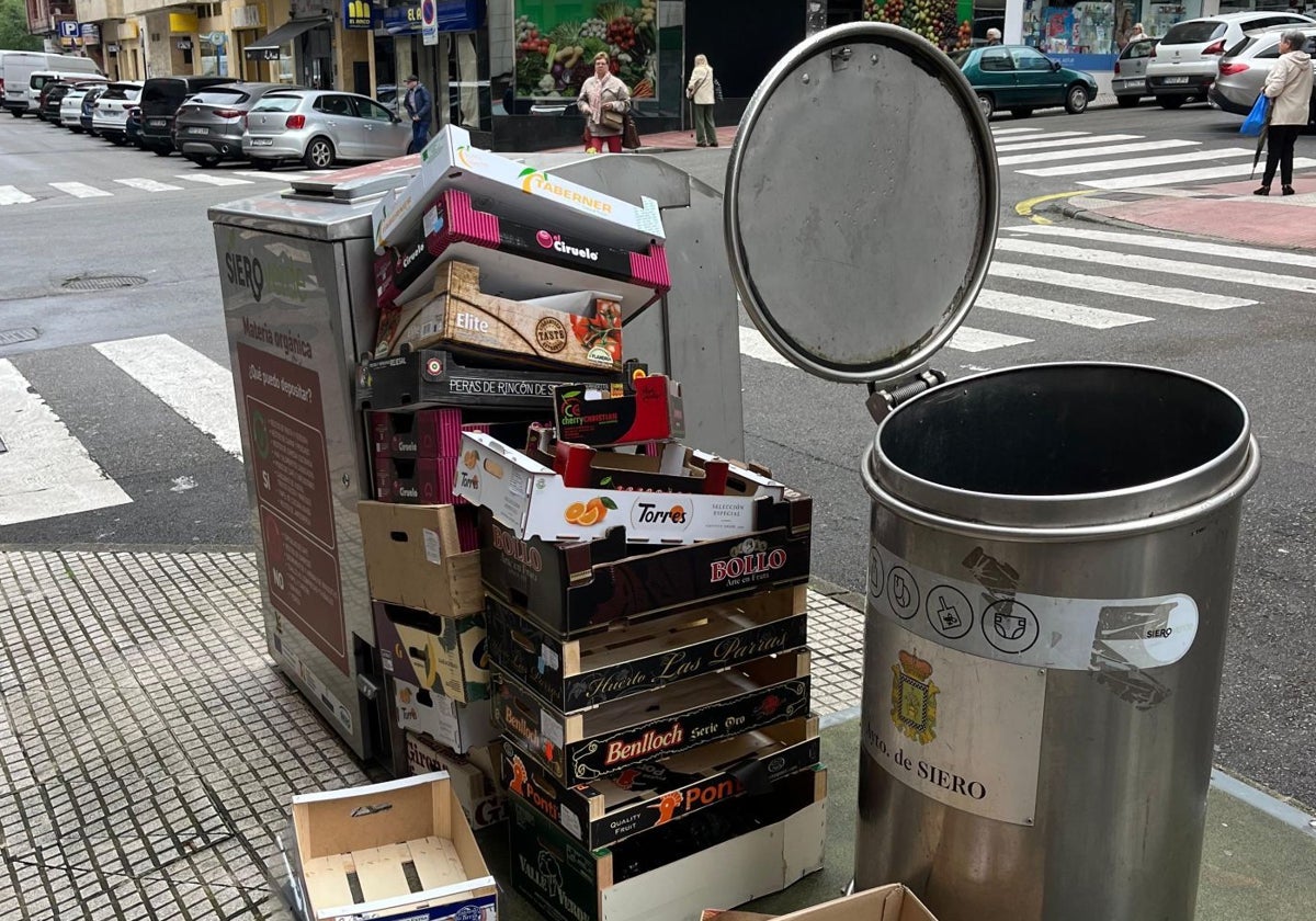 Restos de cajas de los comercios apilados junto a los cubos de basura en pleno centro urbano de Pola de Siero.