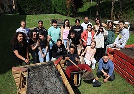 Jóvenes de la asociación Mar de Niebla posan con los huertos elevados que están construyendo en el jardín de los apartamentos del ERA.