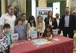 Yago González (alumno), el director del colegio Los Campos, Toni Medina; Samuel Moreno, Irene Porrero, Nelli Gensiurovska, Vira Zghonyk, la vicealcaldesa Ángela Pumariega, el concejal de Atención a la Ciudadanía, Abel Junquera, y el director de Visita Gijón/Xixón, Daniel Martínez, en la presentación del juego.
