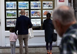 Varias personas observan los anuncios de una inmobiliaria en Oviedo.