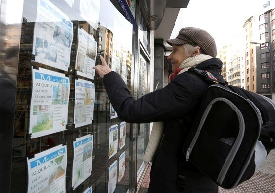 Una ciudadana consulta los anuncios de alquiler de viviendas de una inmobiliaria de Asturias.