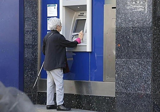 Una mujer saca dinero de un cajero automático.