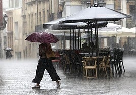 Una mujer, bajo un paraguas durante una fuerte tormenta en Oviedo.