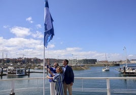 Nieves Roqueñí, Flor Guardado y Jorge González-Palacios izan la Bandera Azul este miércoles en el Puerto Deportivo de Gijon.