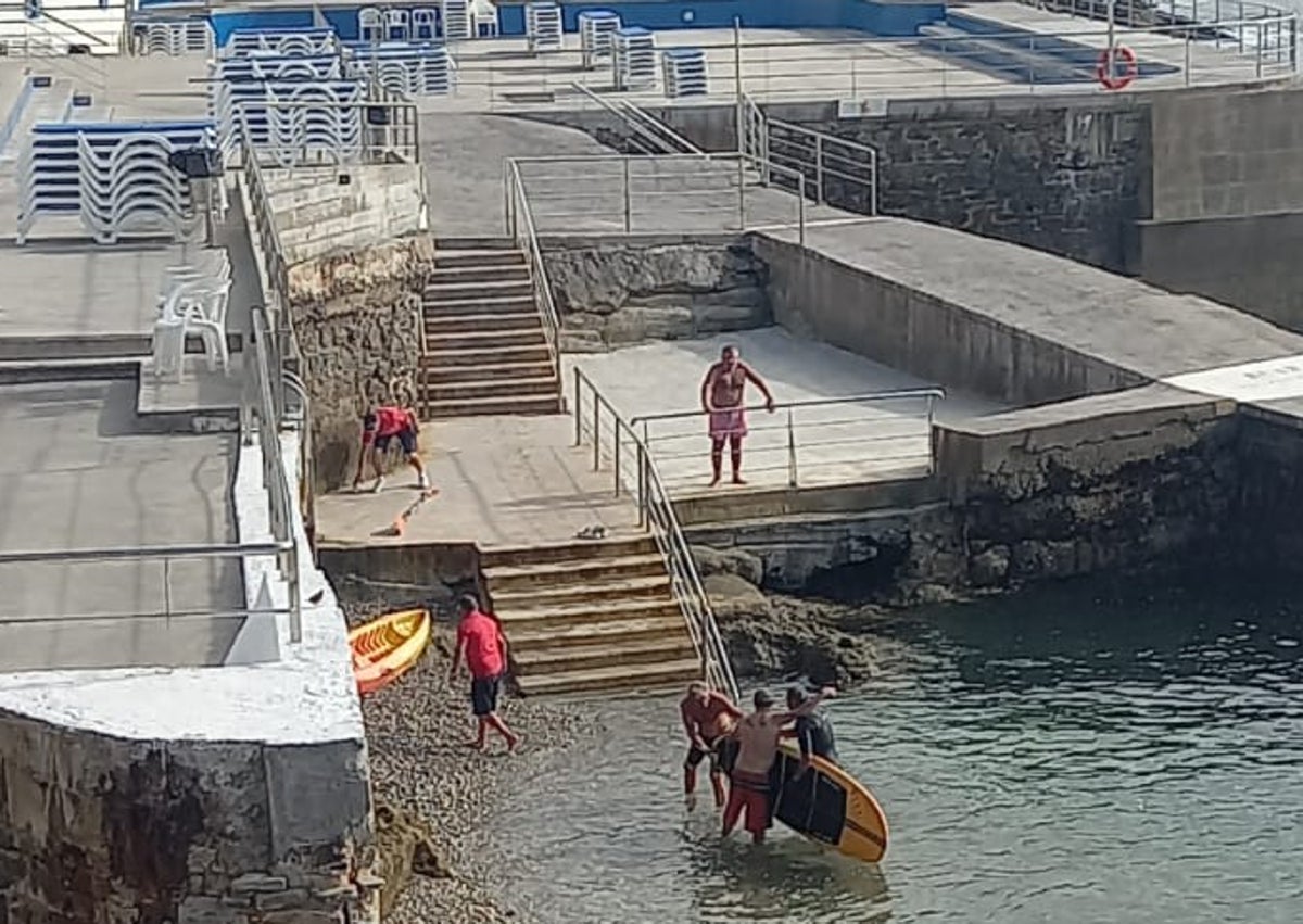 Imagen secundaria 1 - Arriba, momento del rescate del vecino de Cimadevilla de 54 años en la mar a la altura del Club de Regatas. Debajo, S. P. J. se abraza a su rescatador y más abajo, ya escaleras arriba, con bañador rojo.