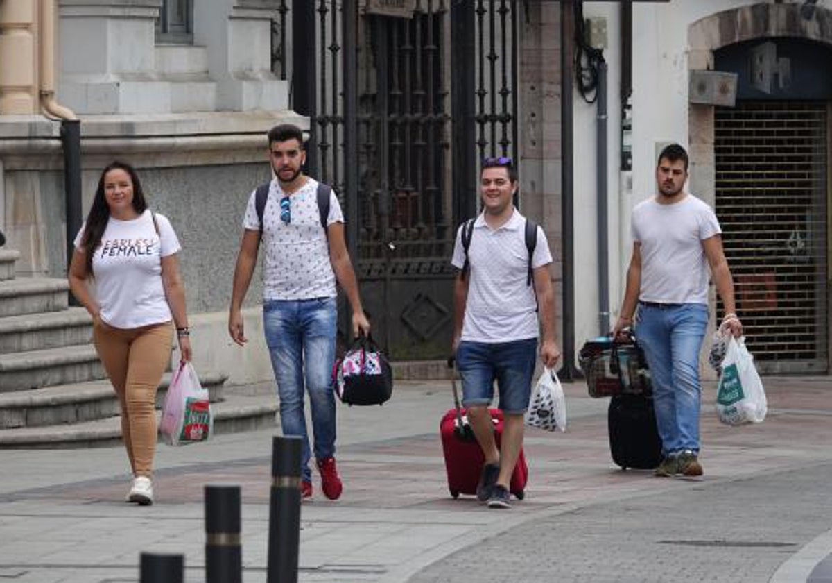 Un grupo de viajeros caminan con sus maletas por Llanes.
