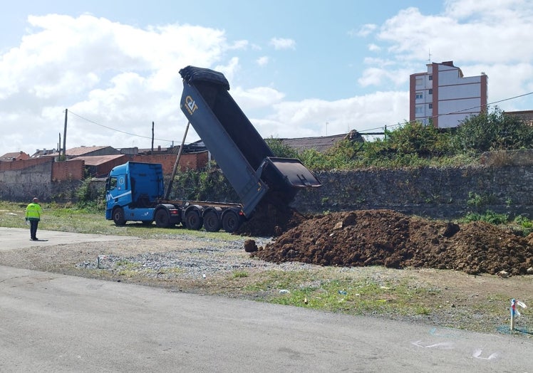 Un camión vuelca tierras procedentes de la Pecuaria en los terrenos de Naval Gijón.