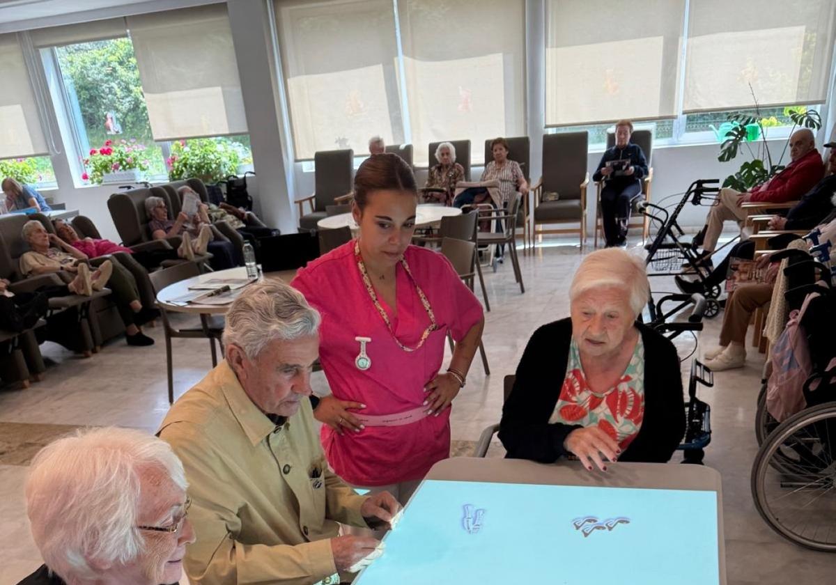 Una profesional de Mejora con residentes en una mesa interactiva.