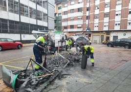 Operarios recogen los restos de los contenedores quemados en la calle la Justicia, en La Felguera, el pasado mes de mayo.