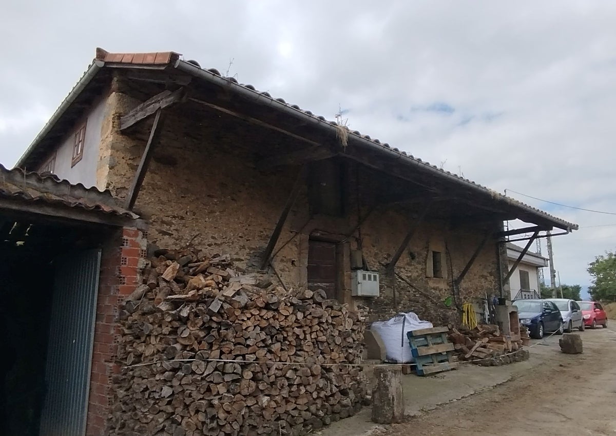 Imagen secundaria 1 - Arriba, José Manuel Fernández e Isabel d'Anuca, con su hija María y el marido de esta, Juan Lorences, en la casa familiar; a la izquierda, la casa 'viecha' de Manulón, donde nació y se crió en los veranos Xuan Bello. A la derecha, una vecina muestra los ejemplares que conserva del escritor.