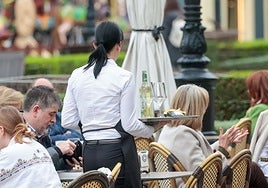 Una camarera atiende a los clientes en una terraza.