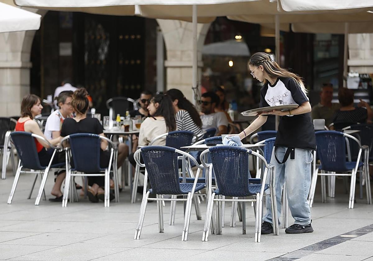 Una camarera sirve las mesas en una terraza de Avilés.