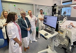 La doctora Consuelo Valles le muestra a la consejera de Salud el sistema de monitorización vídeo-encefalográfica mediante una simulación con un muñeco. Con ellas, la directora del HUCA, Beatriz López, y el enfermero José Aurelio Bartolomé y el médico residente Pedro García.