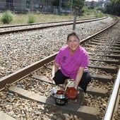 Pilar Meana, con una fabada en su olla ferroviaria, posa en las vías del tren junto a su negocio.