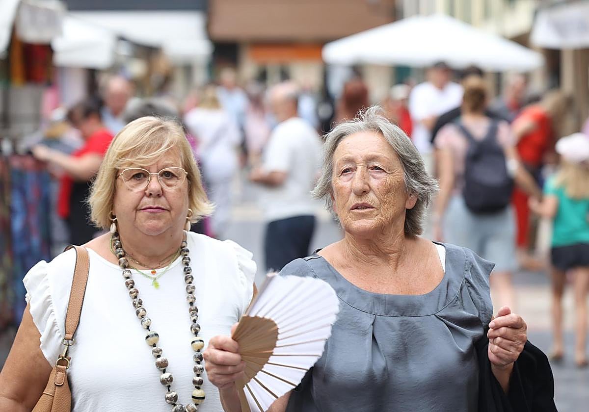 Dos mujeres se abanican, paseando por el casco histórico de Oviedo.