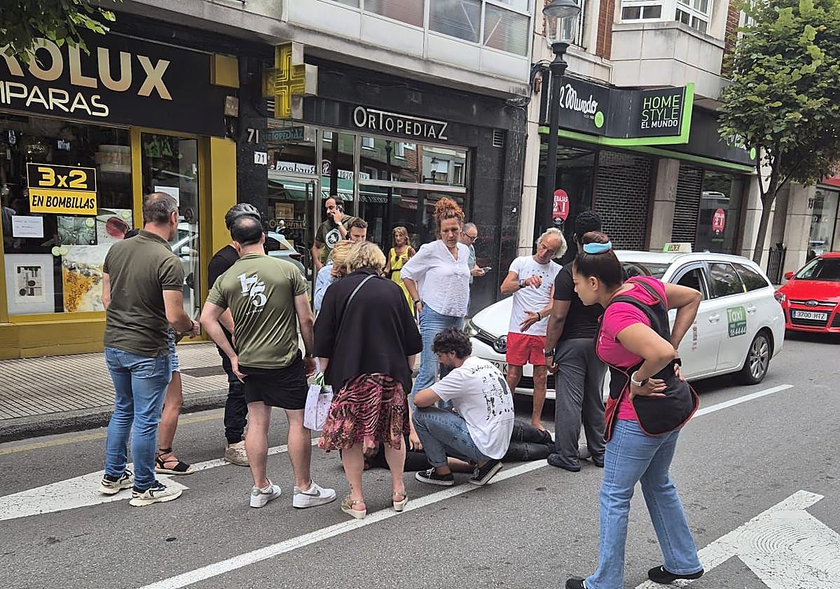 Un grupo de ciudadanos auxilia al conductor del patinete, que quedó tendido en la calzada de la avenida de la Costa.