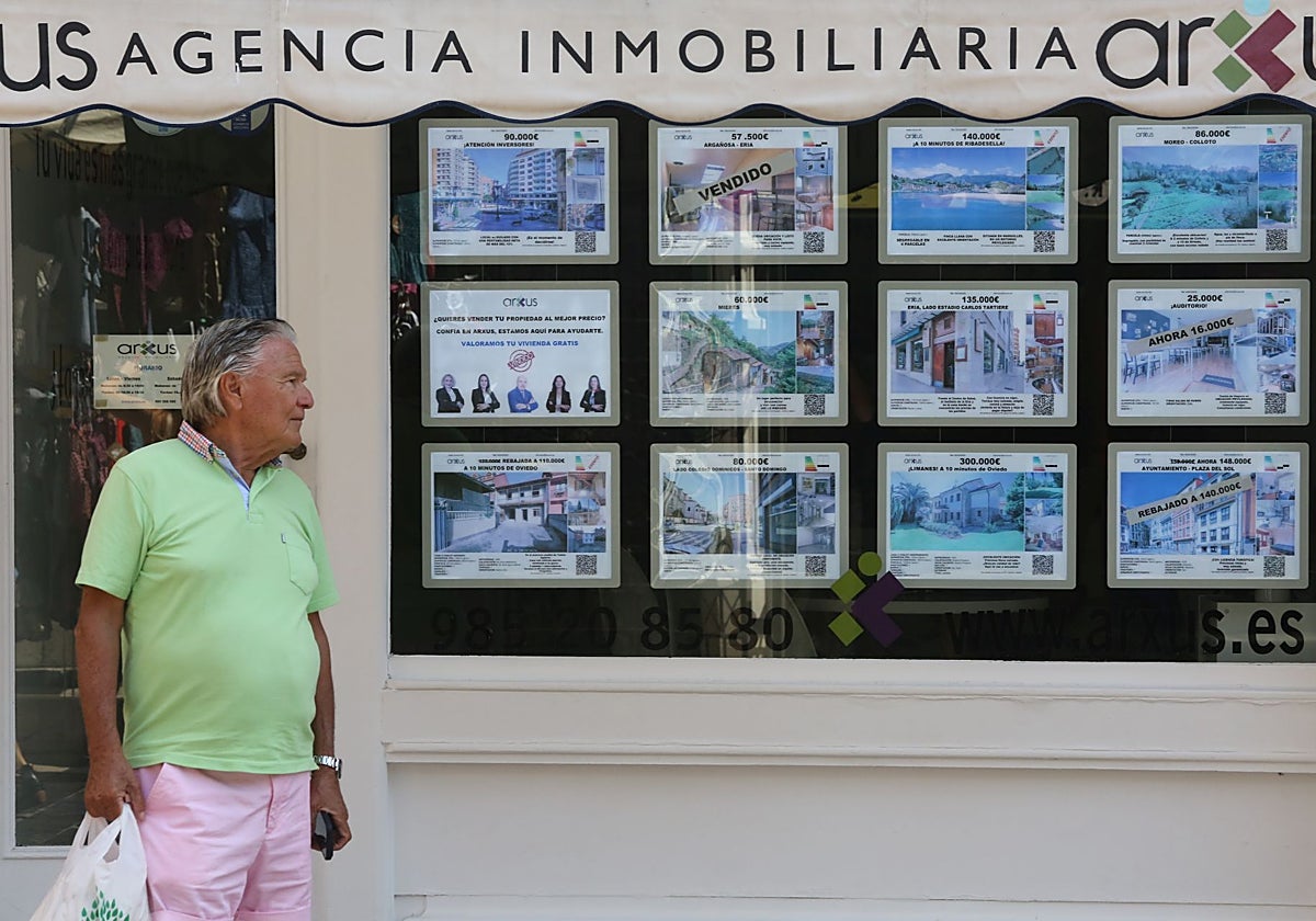 Un hombre pasa por delante del escaparate de anuncios de una agencia inmobiliaria.