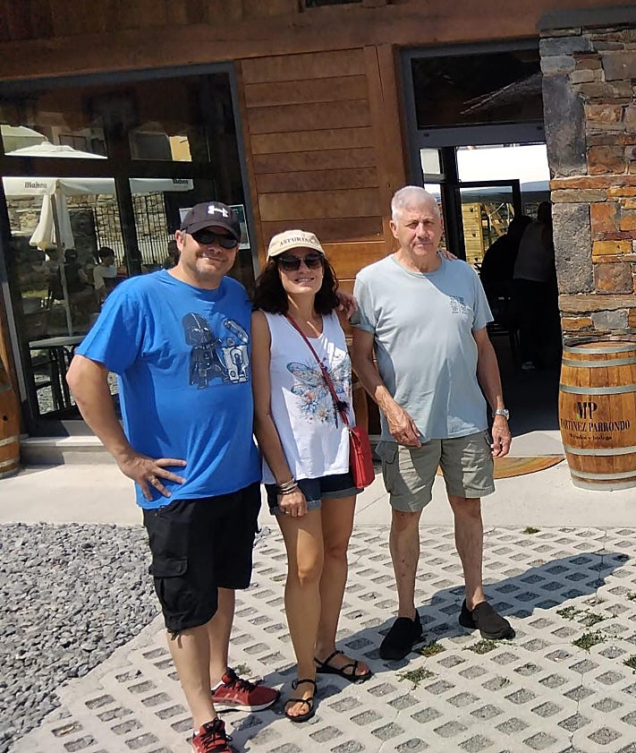 Imagen secundaria 2 - Arriba, ambiente en la playa de Poniente de Gijón. En la imagen central, Manuel Blanco, que pasa estos días de vacaciones con su familia en Besullo (Cangas del Narcea), lanzándose la piscina del recién inaugurado hotel La Rectoral. Y, sobre estas líneas, Ángel e Irene Monge, y Daniel del Castillo, madrileños, ante el bar de Moal.