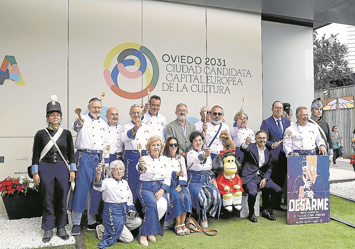 Cofrades del Desarme, cuchara de madera en alto, junto a los concejales presentes en la Feria de Muestras de Gijón.